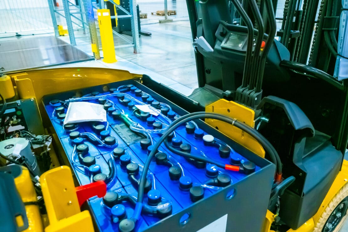 A disassembled electric forklift with its battery exposed.